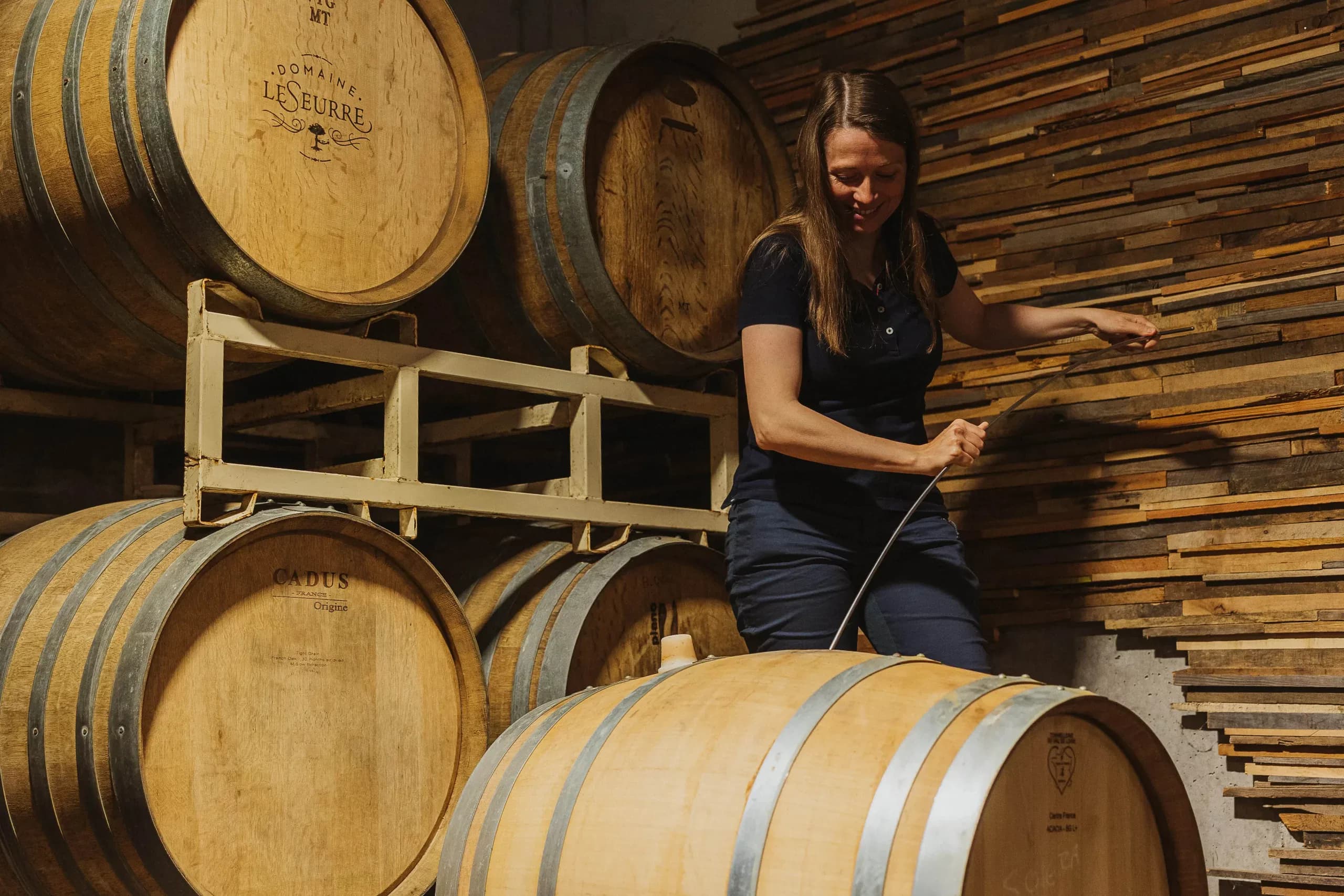 Céline drawing wine from a barrel in the cellar