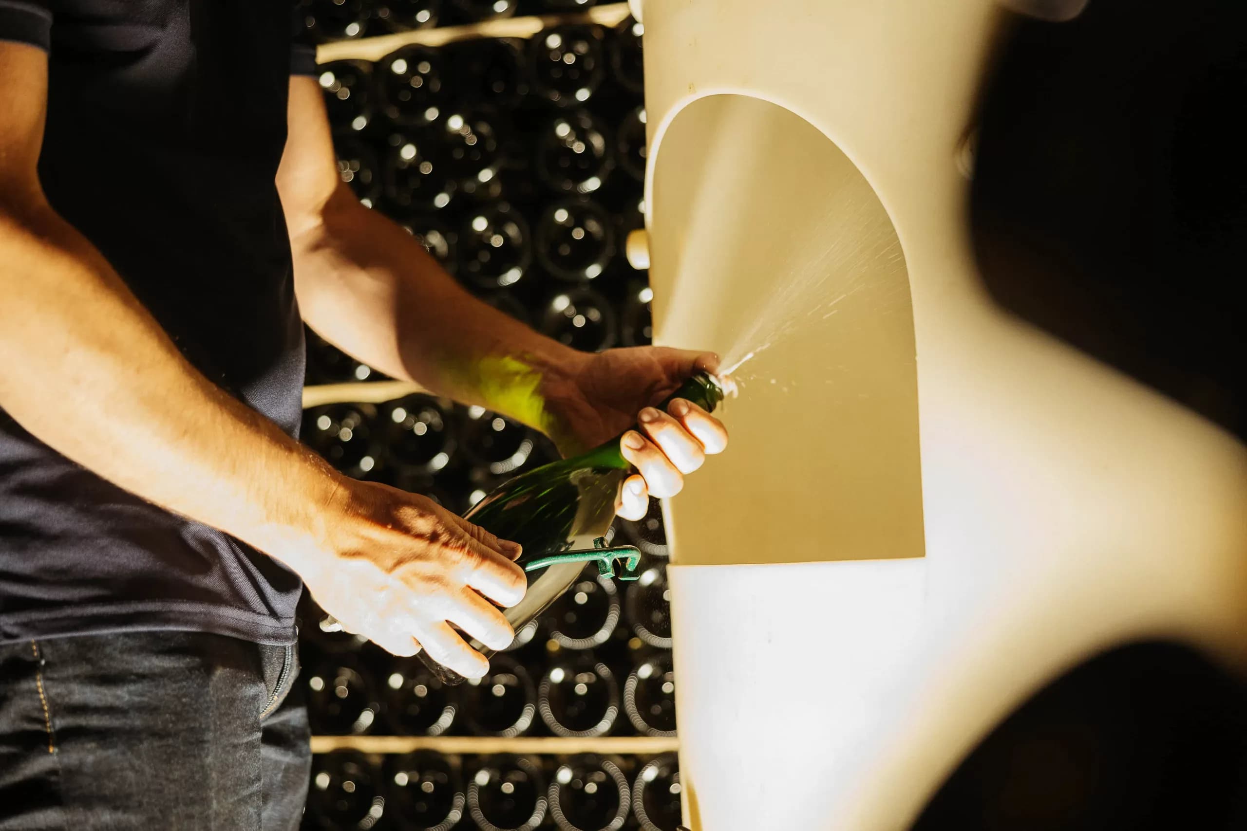 Sébastien LeSeurre disgorging a bottle of méthode champenoise sparkling wine by hand in the cellar