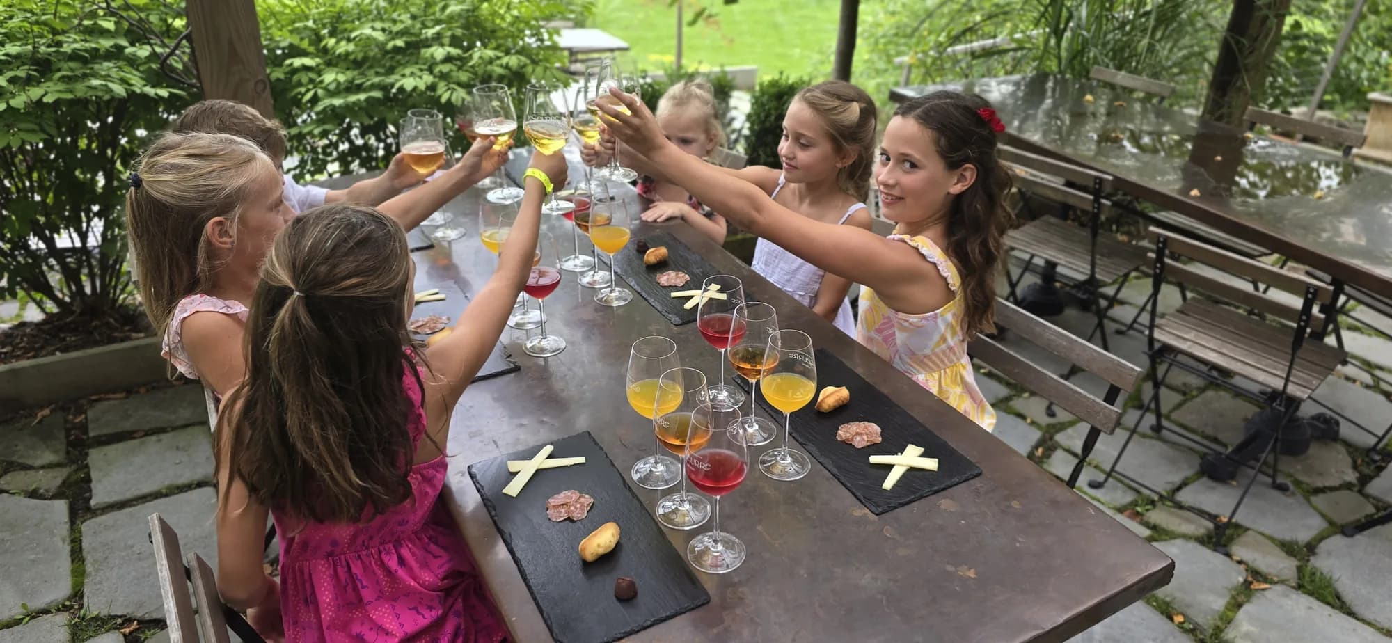 Children raising their glasses together around the tasting table